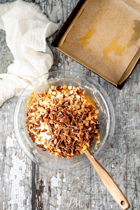 A bowl filled with nuts and a wooden spoon.