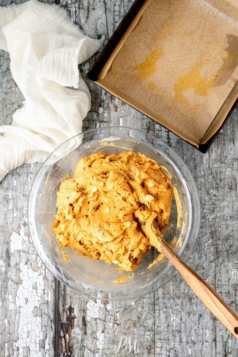 A bowl of dough with a wooden spoon next to it.