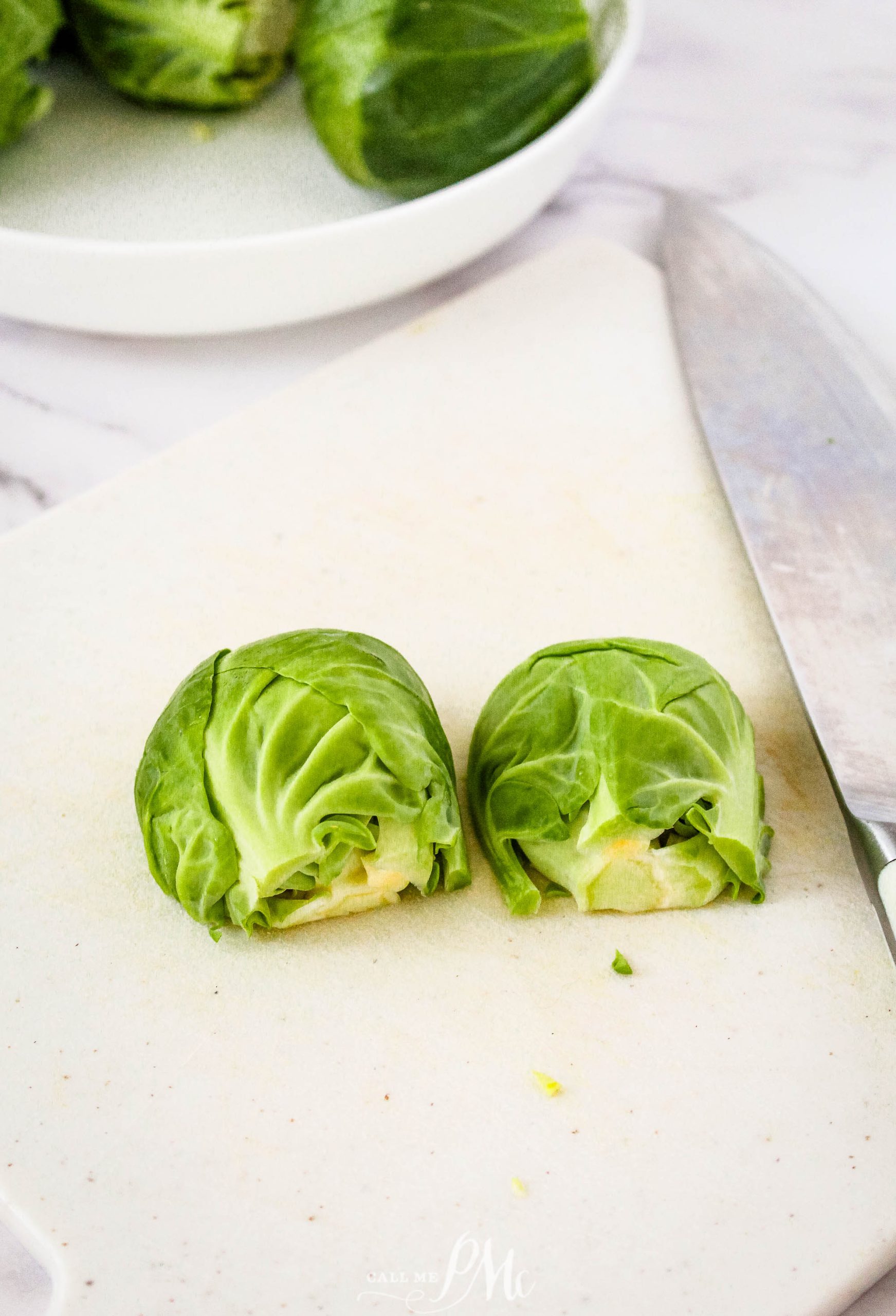 Brussels sprouts on a cutting board next to a knife.