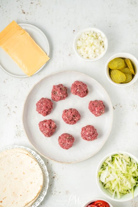 A plate with meatballs, cheese, lettuce and other ingredients.