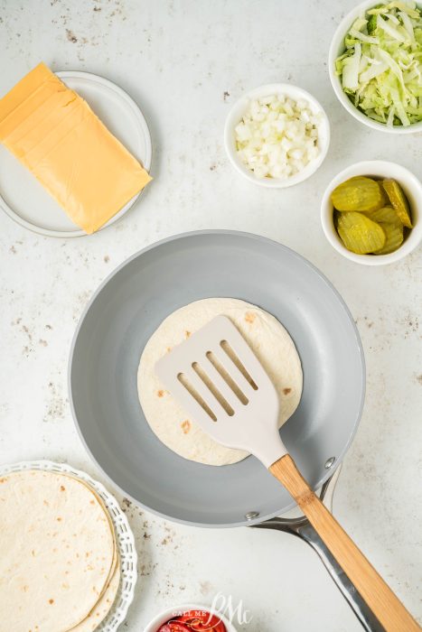 A frying pan with tortillas, cheese and other ingredients.