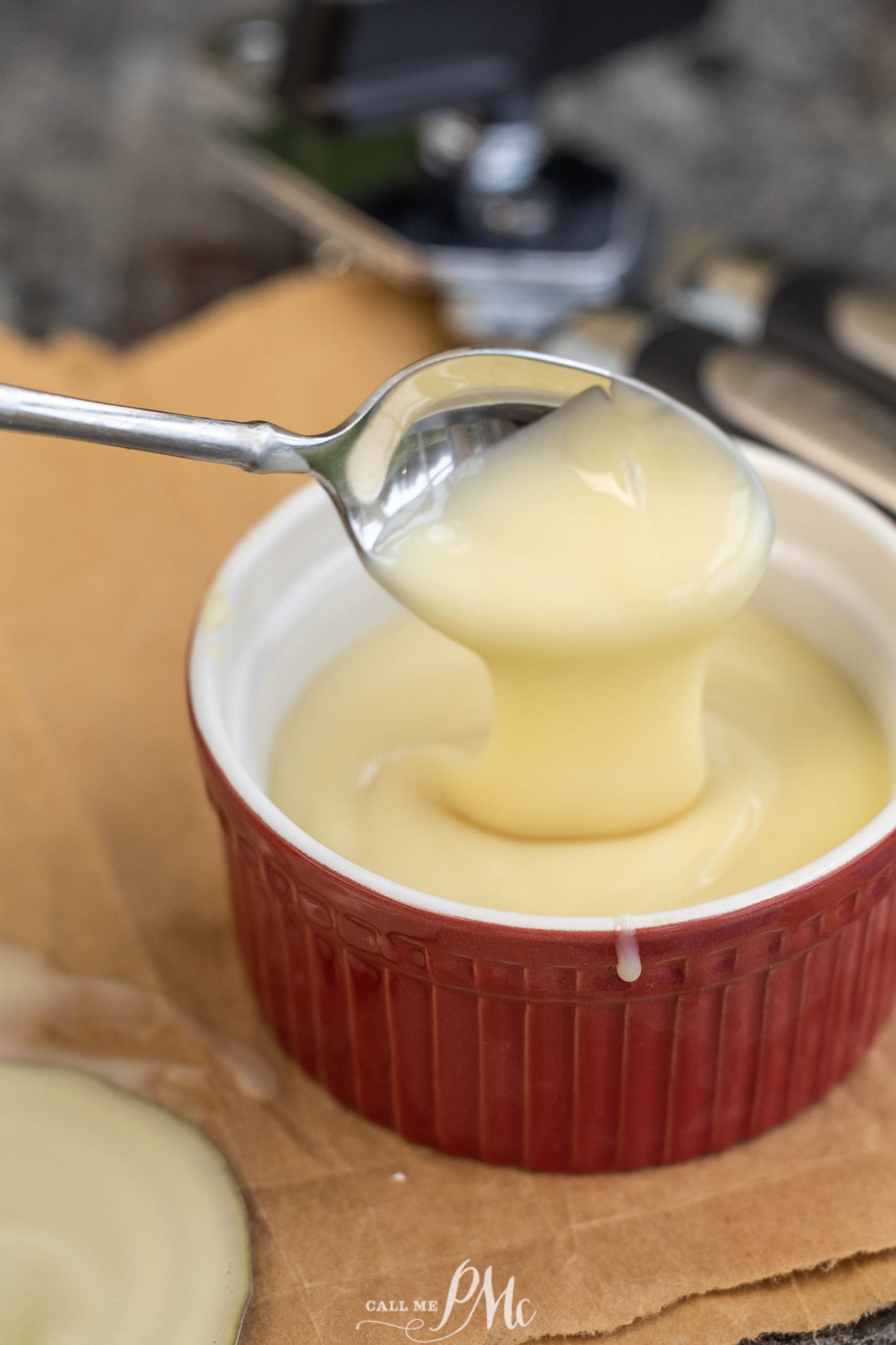 A spoon is pouring a SWEETENED condensed milk into a bowl.