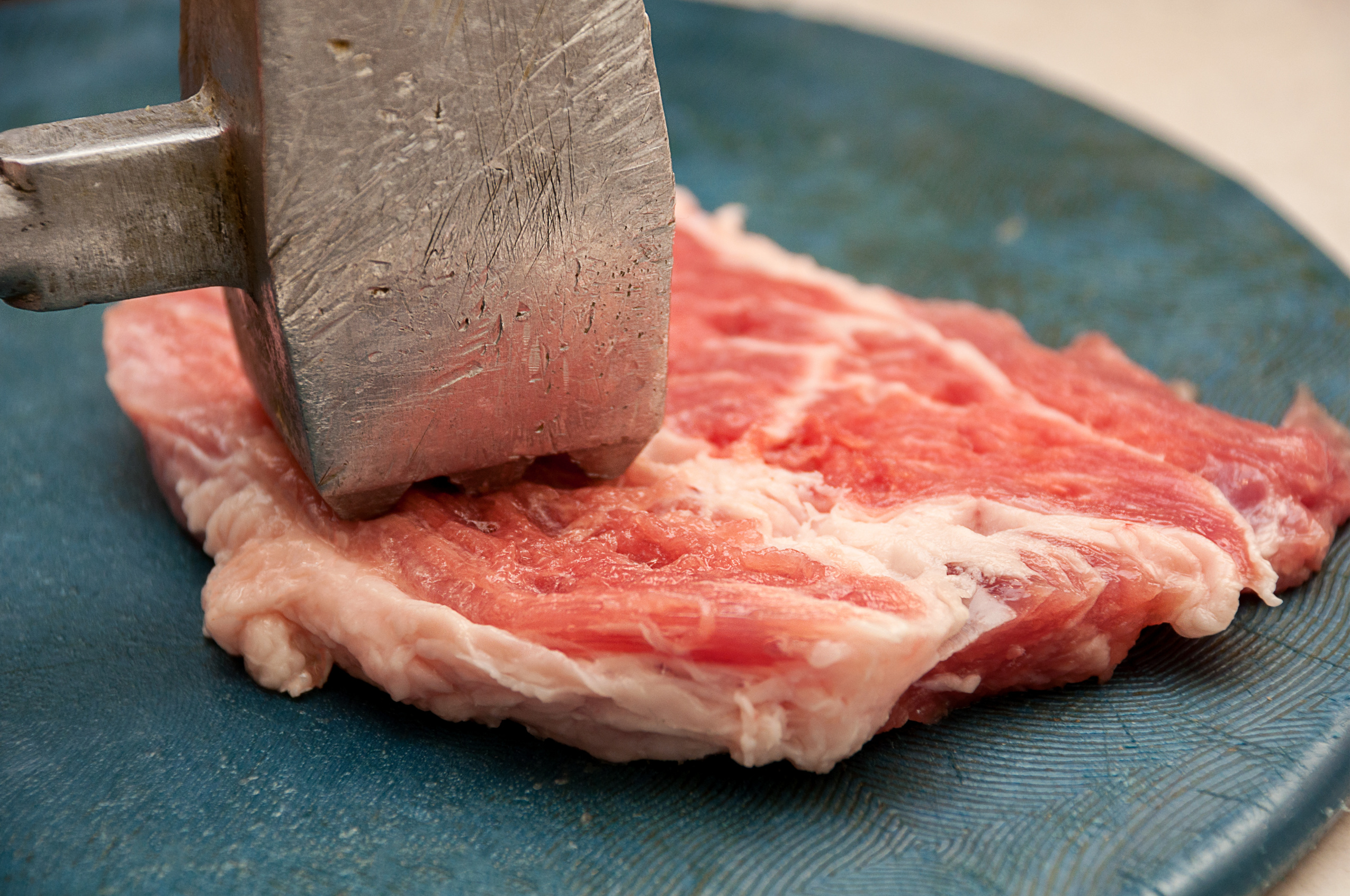 A mallet is being used on a meat