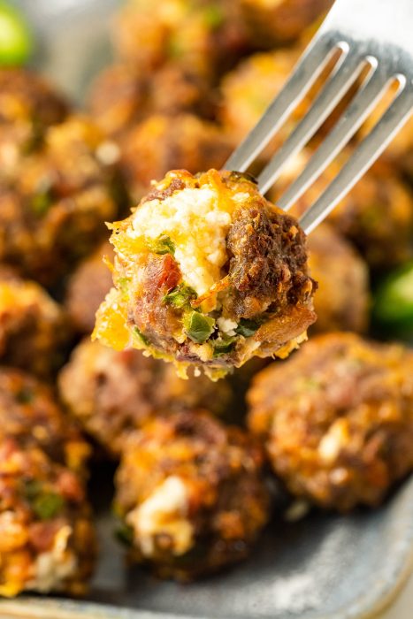 Jalapeno Popper Meatballs on a fork on a plate.