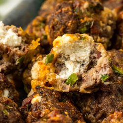 Meatballs with cheese and jalapenos on a plate.
