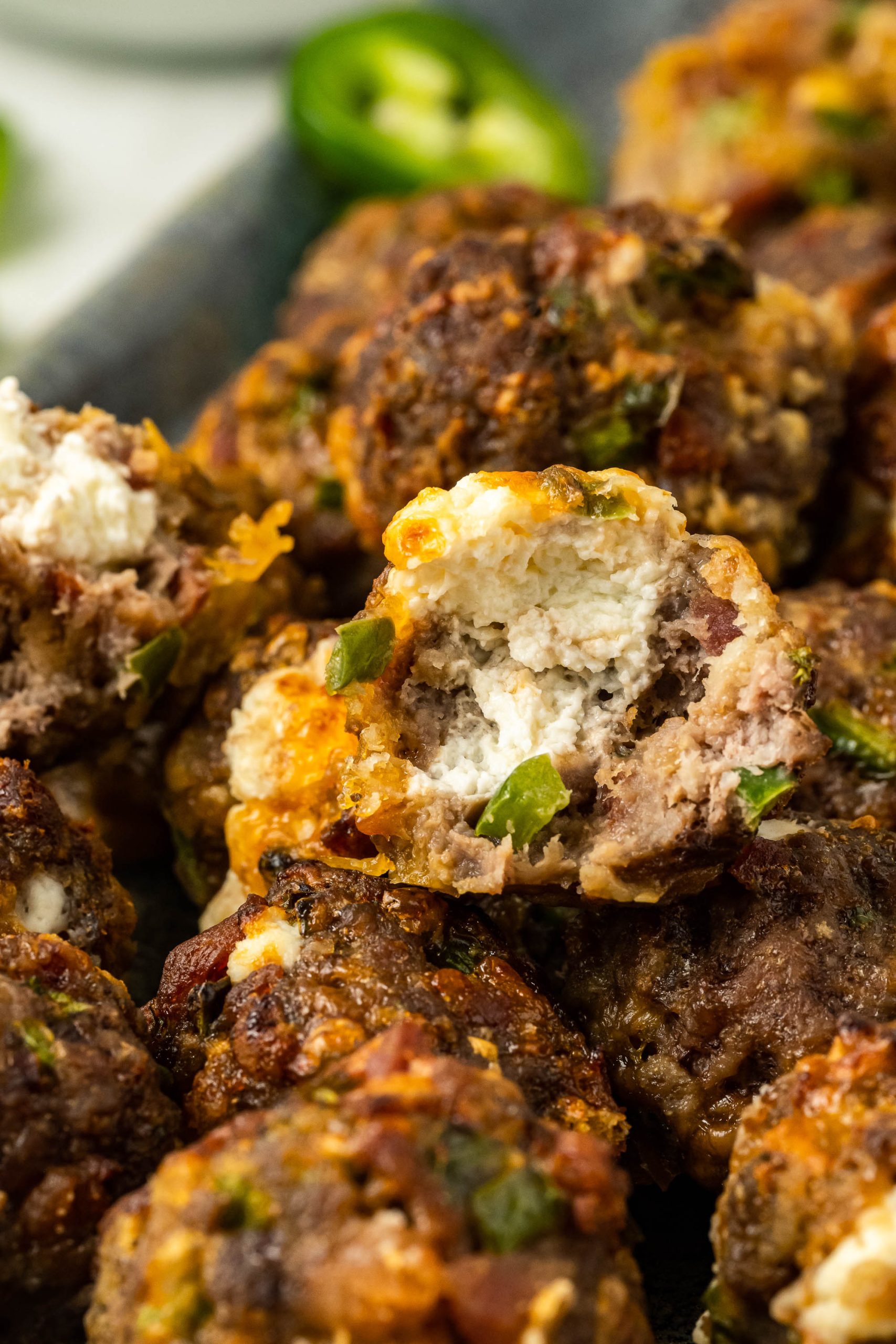 Meatballs with cheese and jalapenos on a plate.