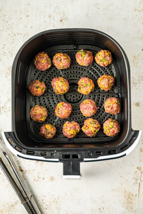 An air fryer filled with meatballs and chopsticks.