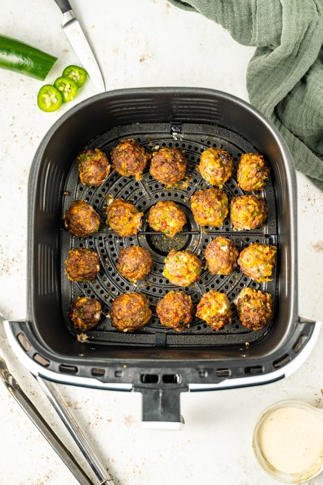 Air fryer filled with meatballs and jalapenos.