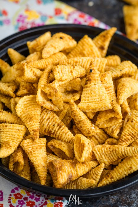Bugles Chex Mix in a bowl on a colorful tablecloth.