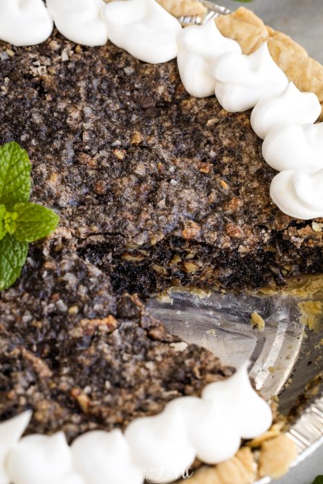 A pie with whipped cream and a mint leaf on top.