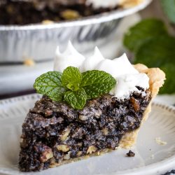 A slice of Chocolate Sawdust Pie with whipped cream and mint leaves.