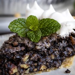A slice of Chocolate Sawdust Pie with whipped cream and mint leaves.
