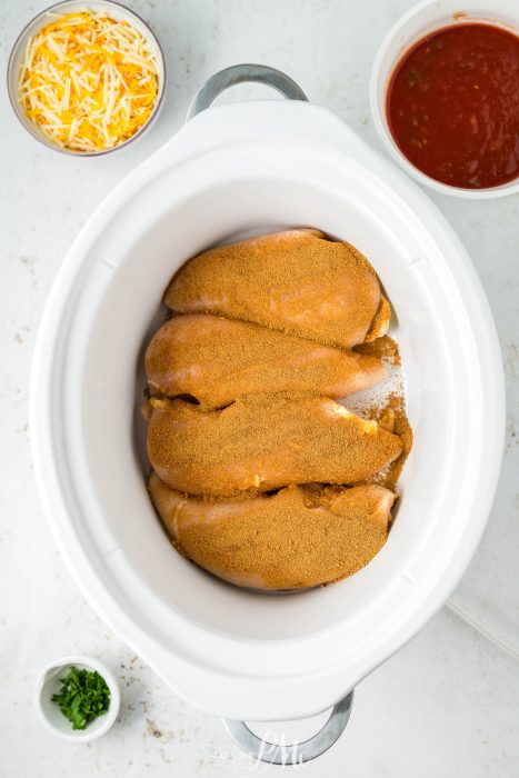 A white crock pot with a couple of sauces in it.