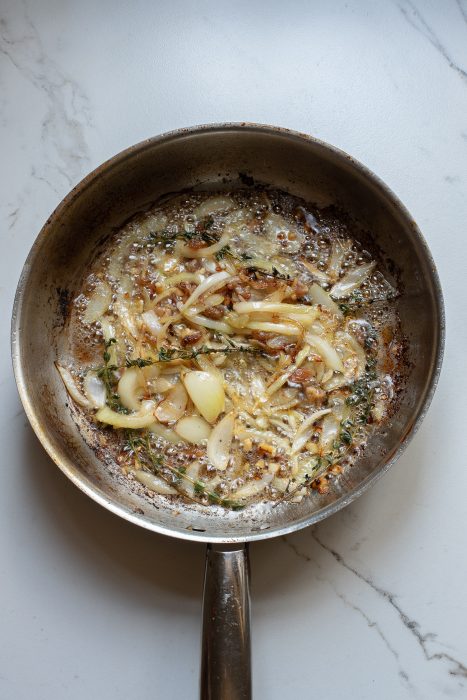 A frying pan with onions and garlic in it.