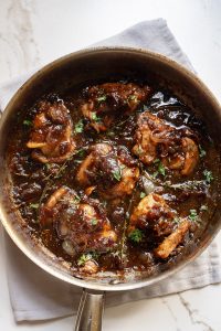 A frying pan with chicken in a sauce.