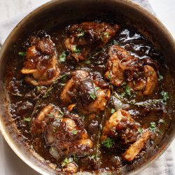 A frying pan with chicken in a sauce.