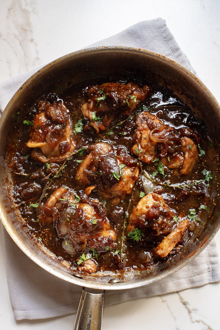 A frying pan with chicken in a sauce.