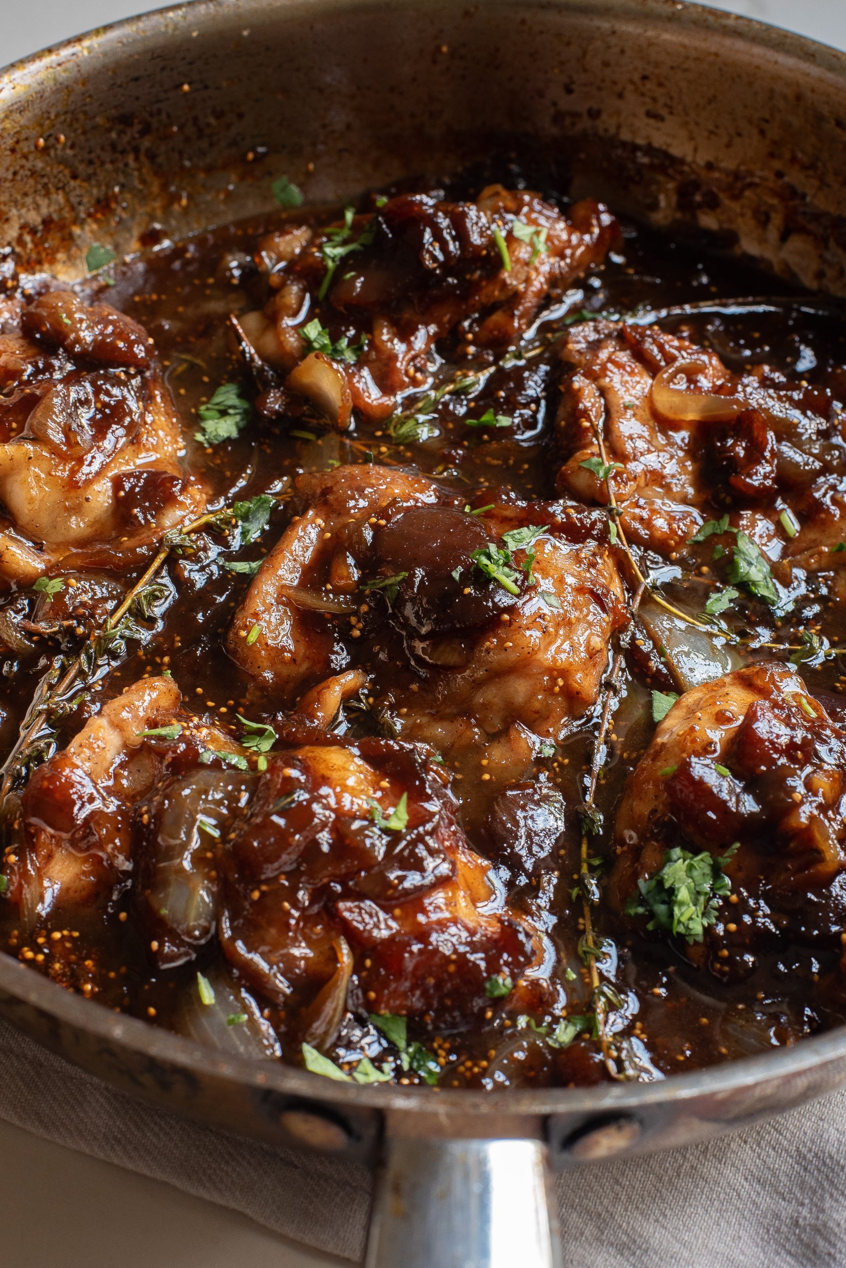 A frying pan filled with chicken in a sauce.