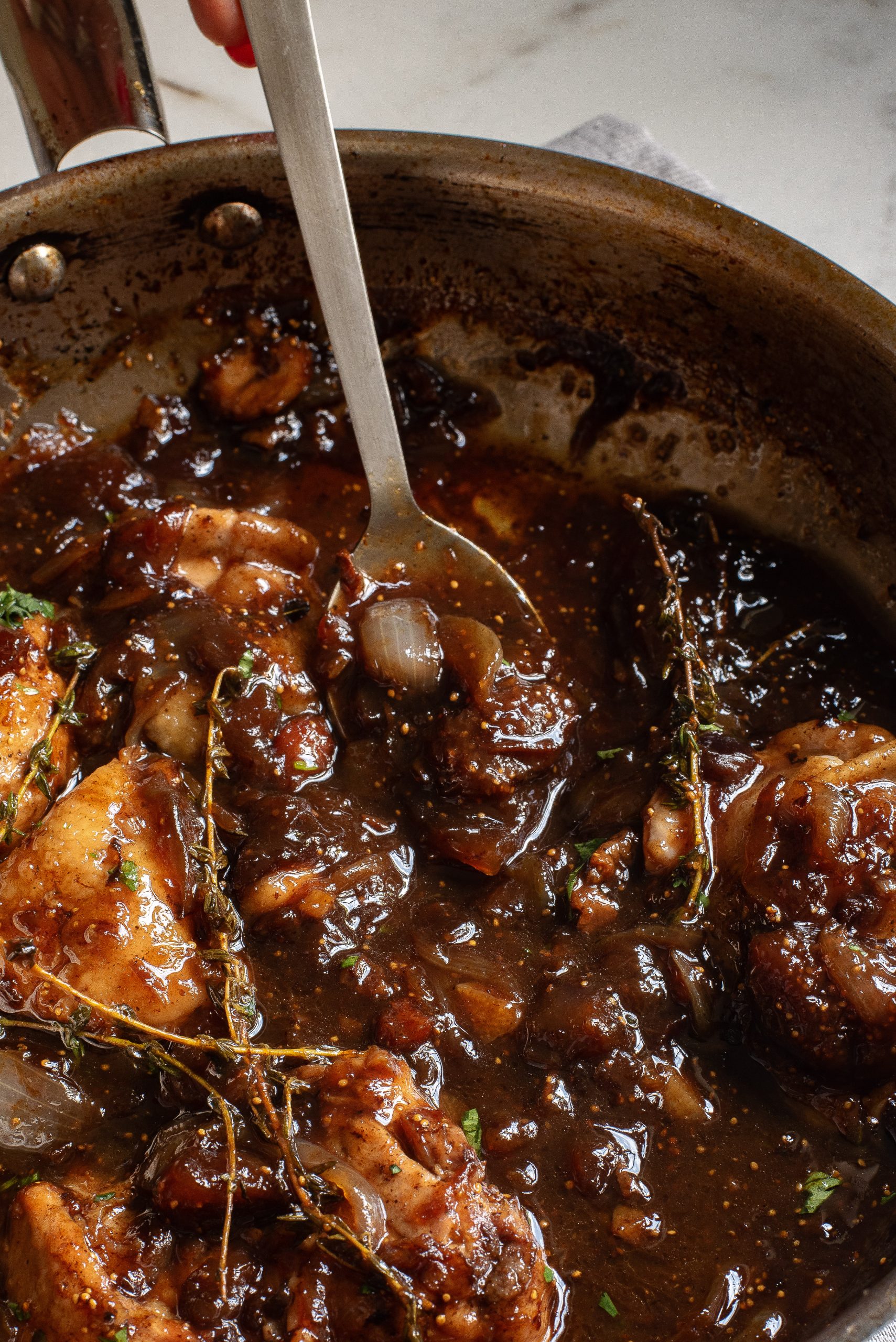 A pan with chicken in a sauce with herbs.