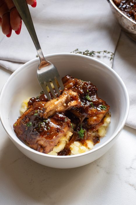 A bowl of chicken with gravy and mashed potatoes.