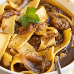 A bowl of soup with French Onion Noodle Soup.