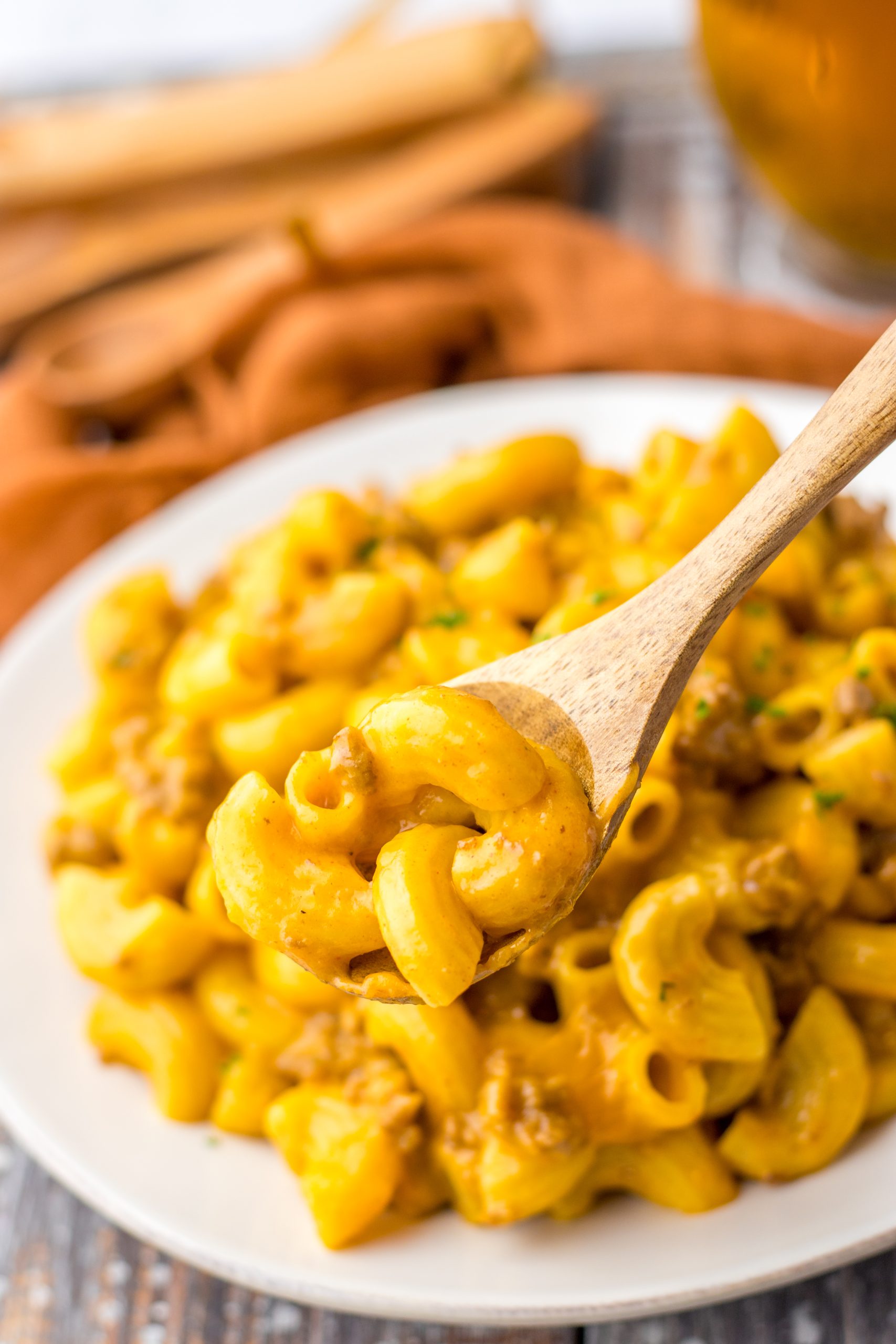 Macaroni and cheese in a bowl with a wooden spoon.