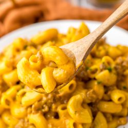 Macaroni and cheese in a bowl with a wooden spoon.