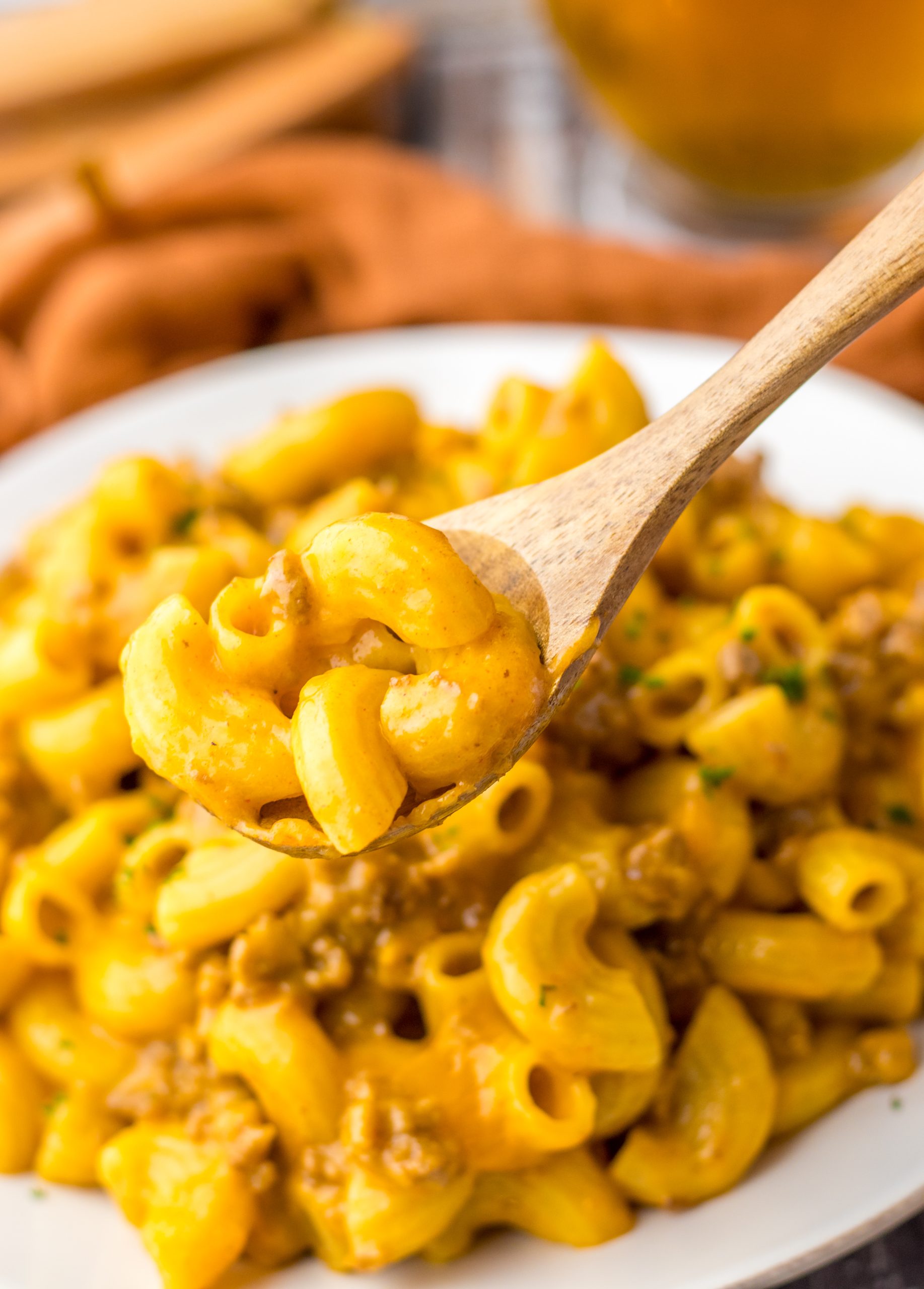 Macaroni and cheese in a bowl with a wooden spoon.