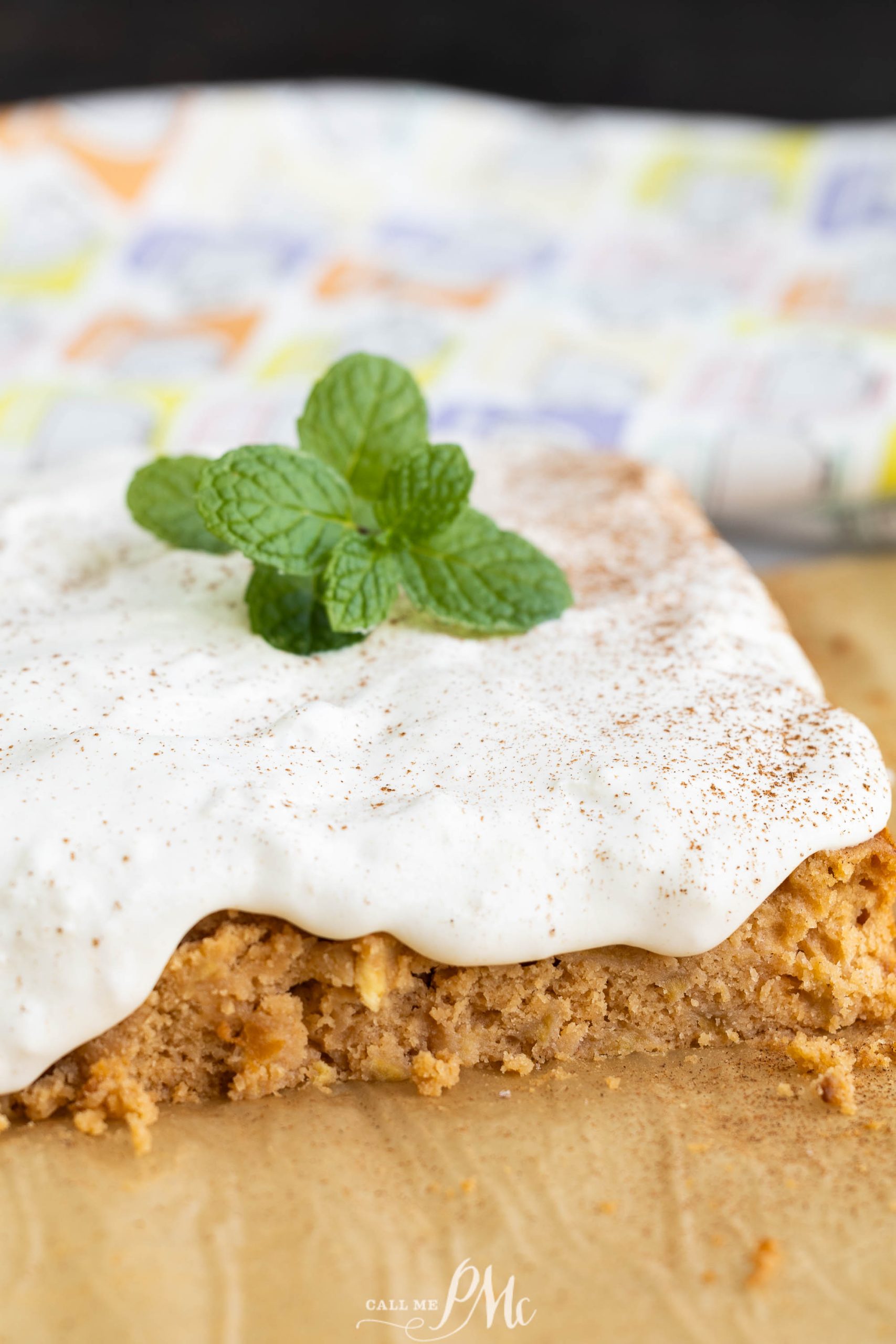 A slice of pumpkin cake with whipped cream and mint leaves.