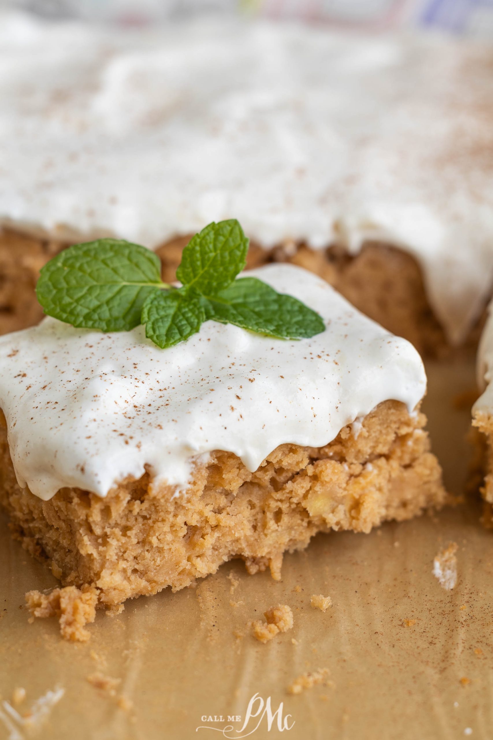 A piece of cake with icing and mint leaves.