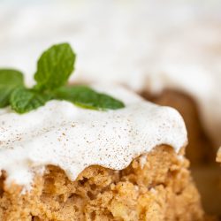 A piece of cake with icing and mint leaves.