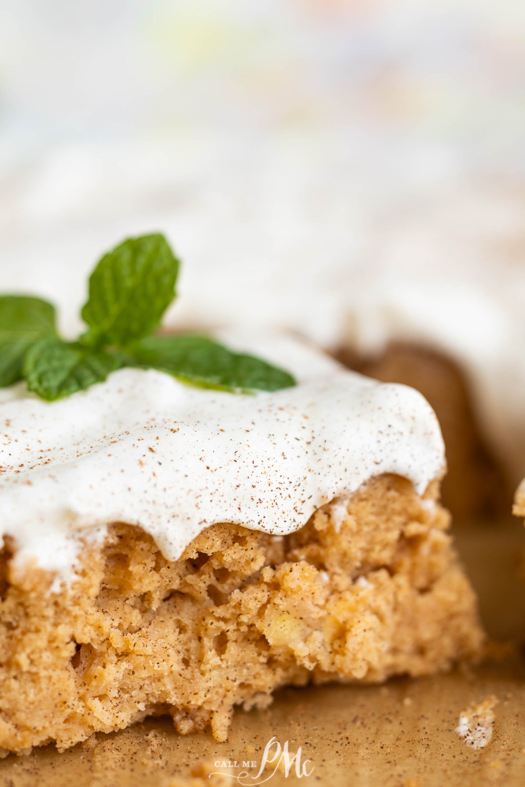 A piece of cake with icing and mint leaves.