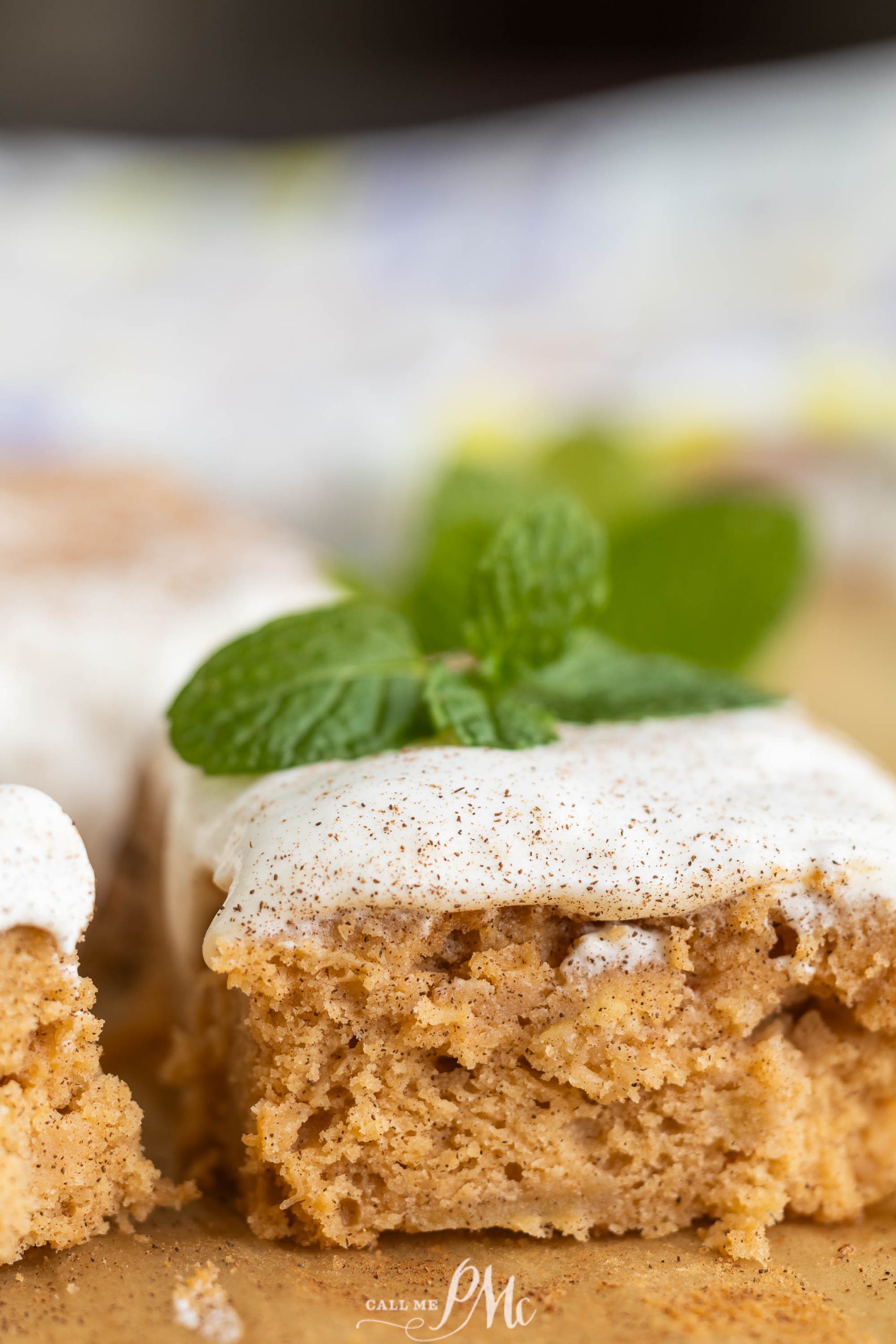 A slice of cake with icing and mint leaves.