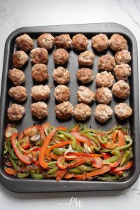 Meatballs and peppers on a baking sheet.