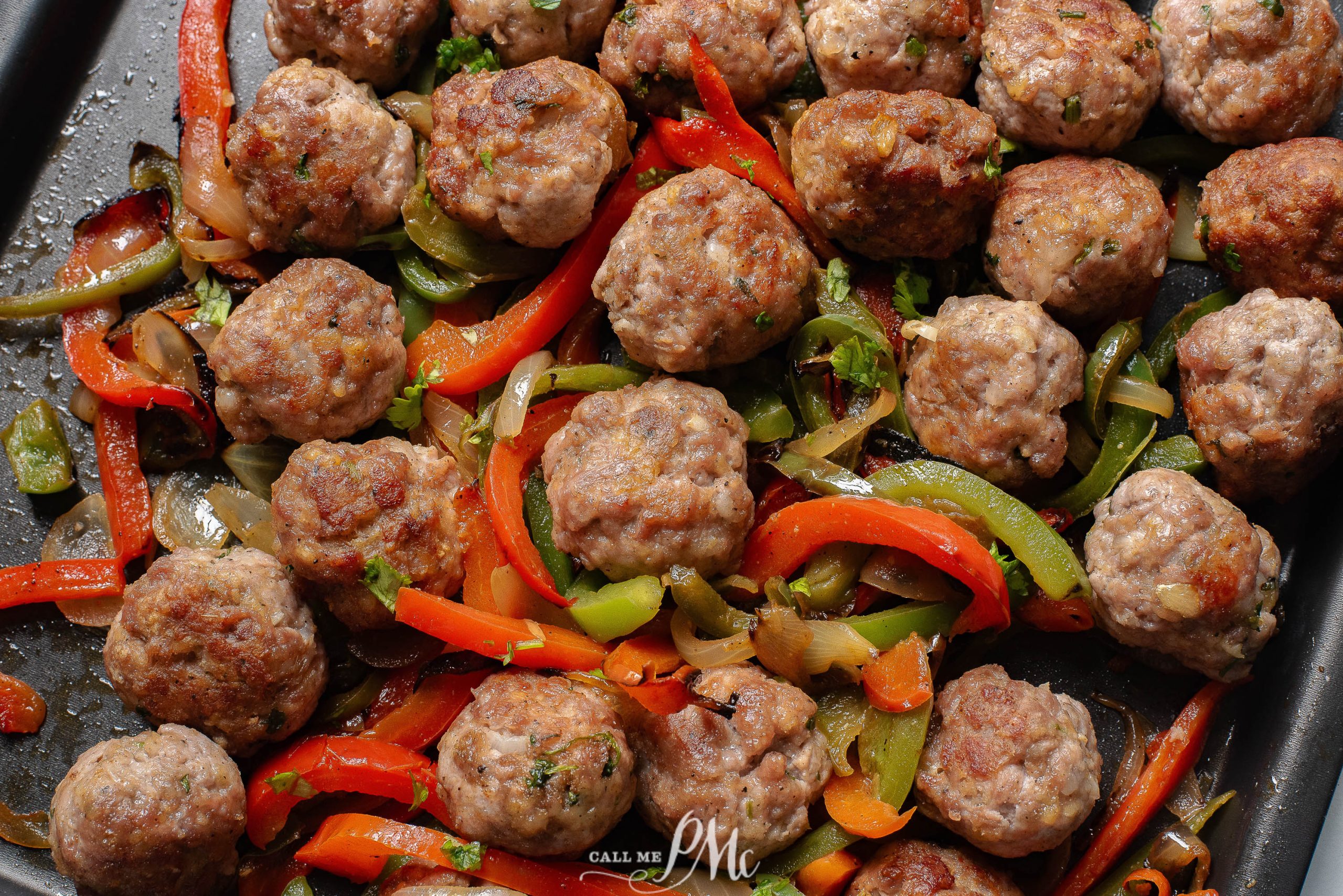 Meat with peppers and onions on a baking sheet.