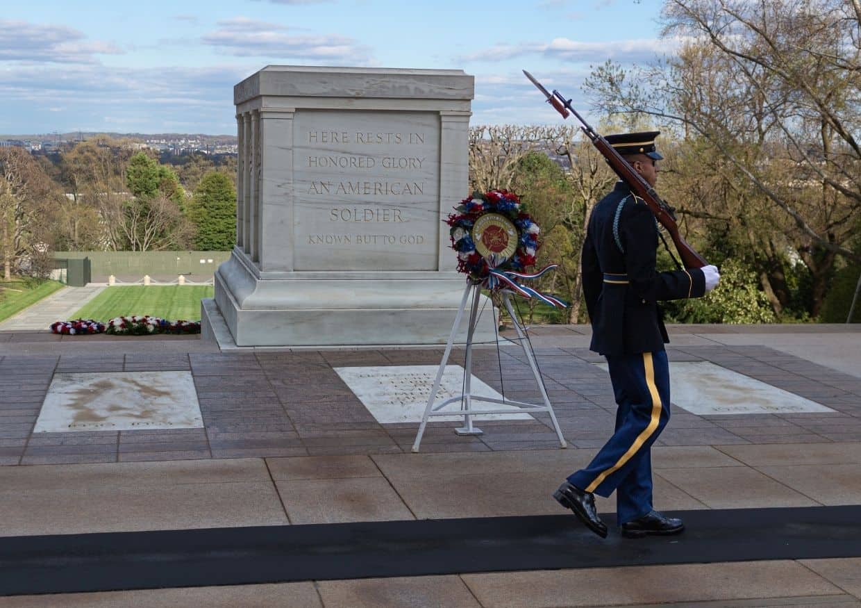 A soldier is standing in front of a monument.