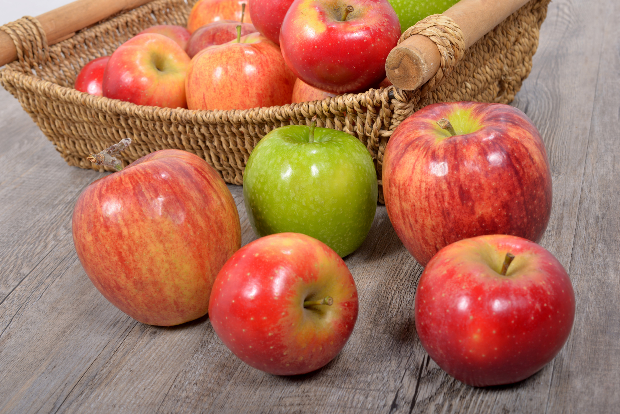 A basket full of apples on a wooden table.