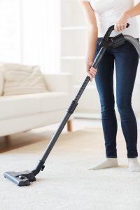 A woman vacuuming a carpet in her living room.