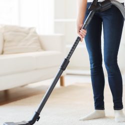 A woman vacuuming a carpet in her living room.