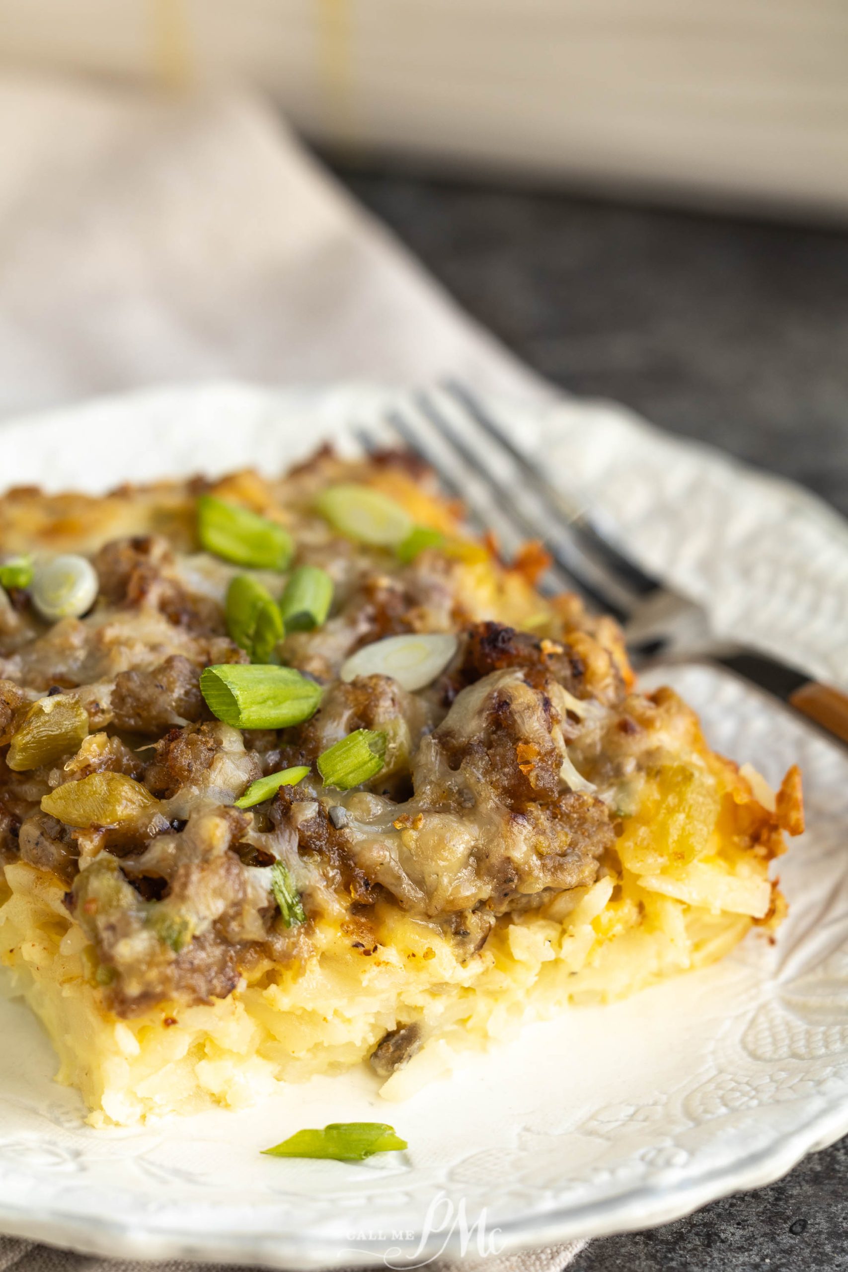 A piece of cheesy hashbrown casserole on a plate.