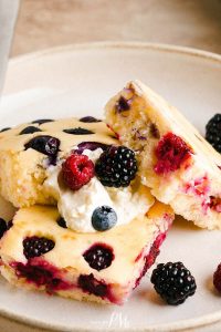 A plate of sheet pan pancakes with whipped cream and berries.