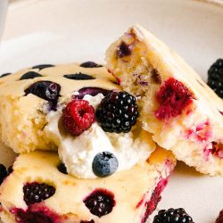 A plate of sheet pan pancakes with whipped cream and berries.