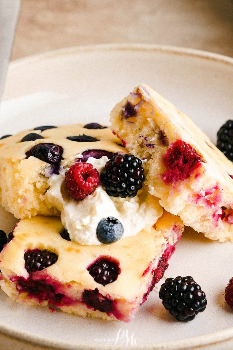 A plate of sheet pan pancakes with whipped cream and berries.