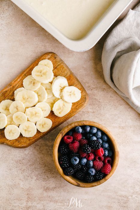 A bowl of berries and bananas next to a bowl of ice cream.