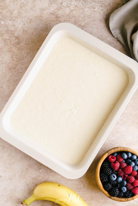 A white baking dish with a bowl of berries and bananas.