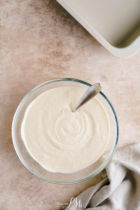 Whipped cream in a glass bowl with a spoon next to it.