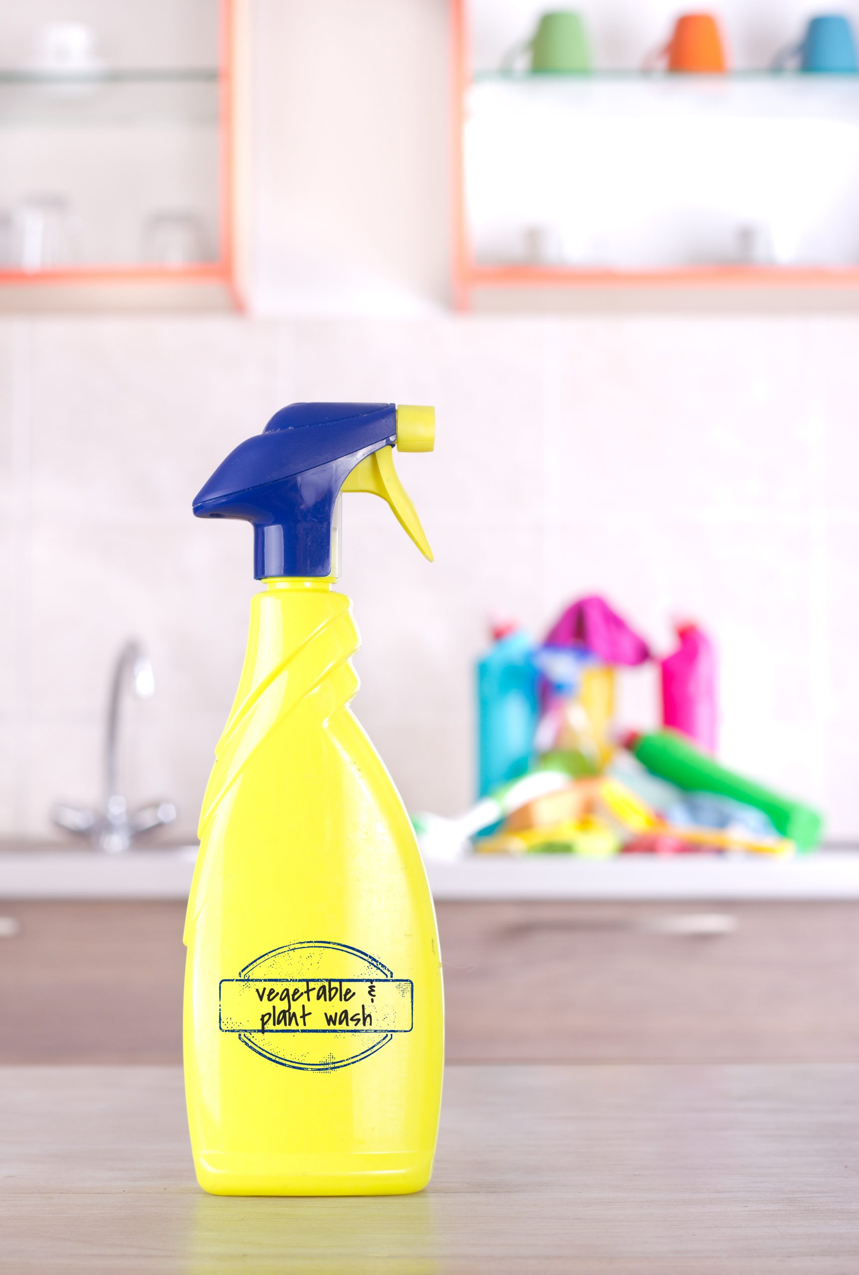 A yellow spray bottle labeled "Organic Pesticide" sits on a table in a kitchen.