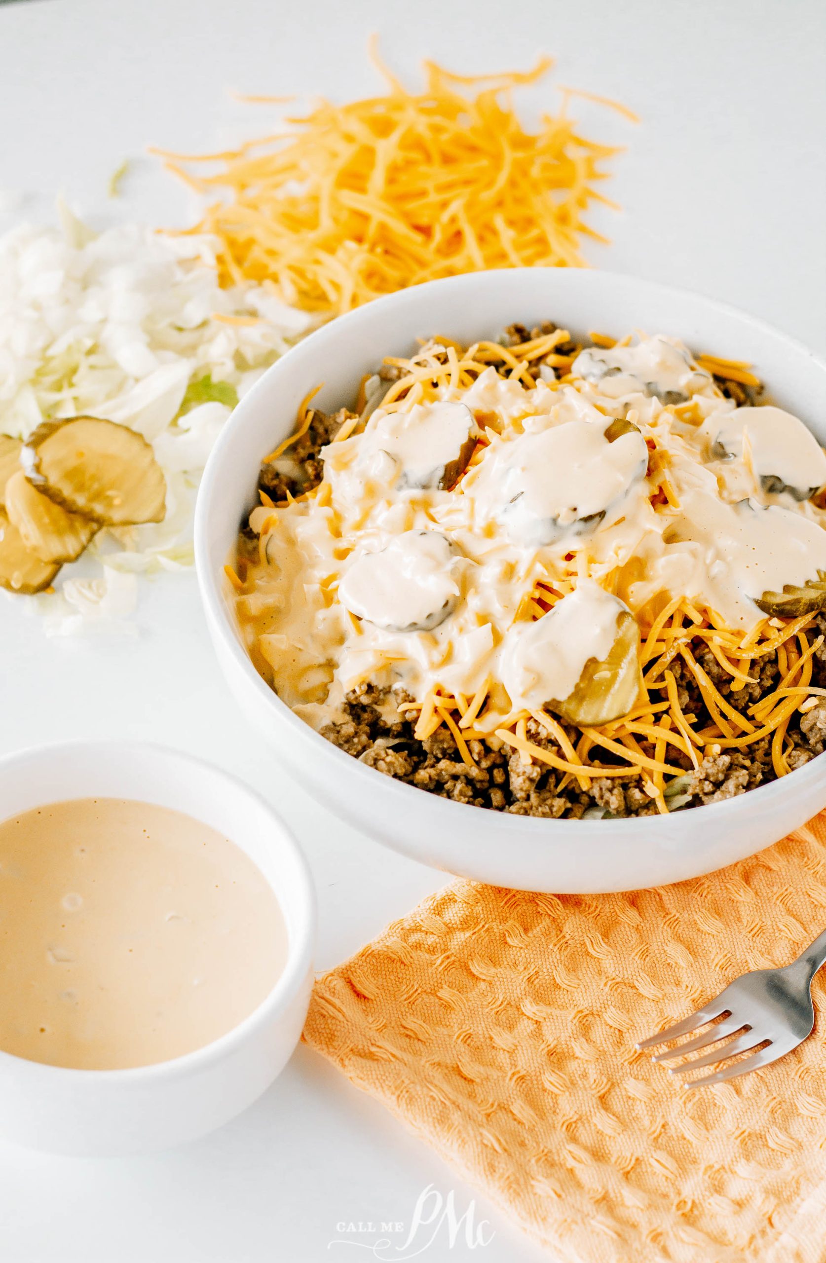 A bowl of nachos with cheese and a fork.