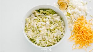 Shredded cabbage and shredded cheese in a bowl.
