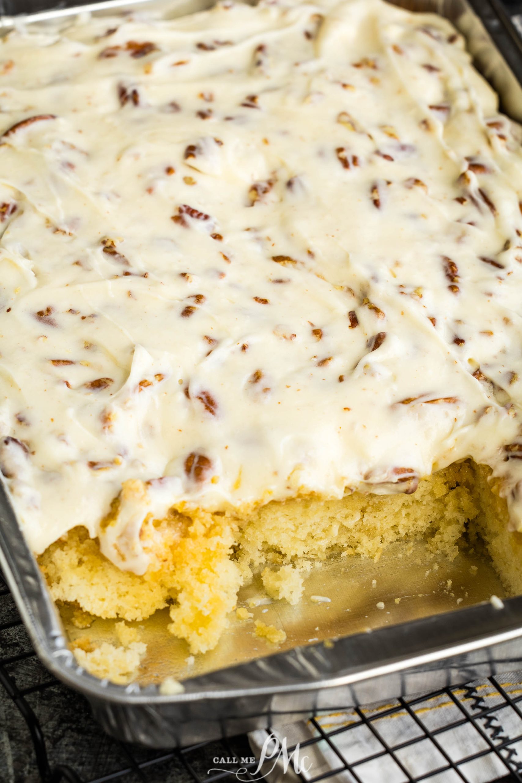 A slice of pecan cake in a pan on a cooling rack.